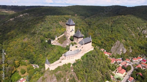 Aerial view on royal castle Karlstejn medieval, state owned castle near Prague in spring nature, lit by evening sun. Romantic Czech castle on the hilltop. Central Bohemia, czech landscape, Czechia