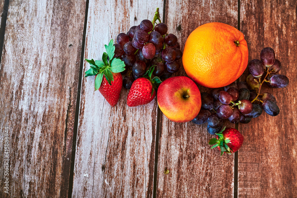 Fresh fruit that lies decoratively in the sunlight on a wooden table.