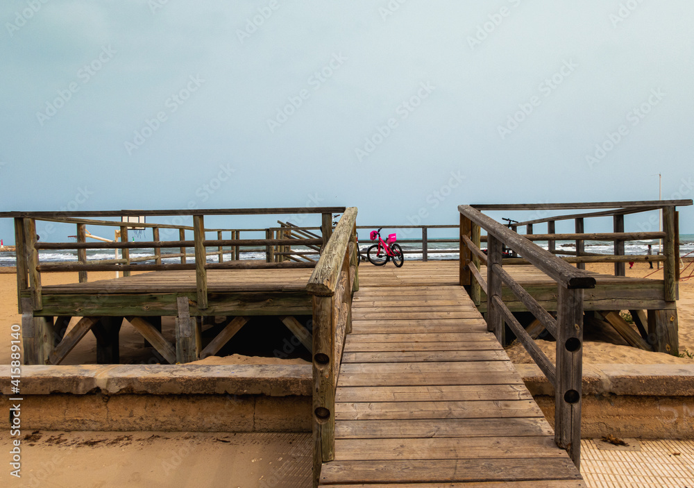 Wooden platform with some bicycles, on a beach with cloudy skies on a cold winter day. Wooden platform with some bicycles, on a beach with cloudy skies on a cold winter day.