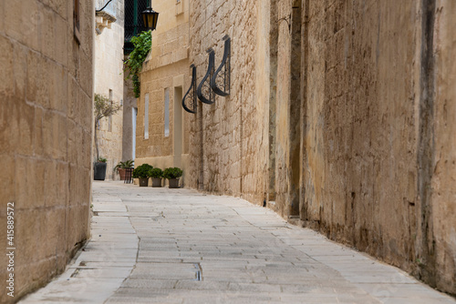 Fototapeta Naklejka Na Ścianę i Meble -  Europe, Malta, Mdina. Typical historic narrow street lined with limestone buildings.