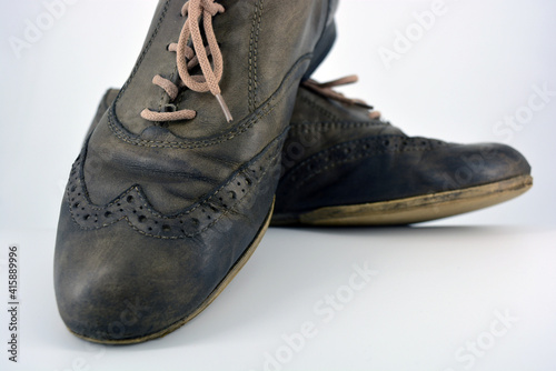 Female leather shoes located on a white background. Oxford shoes with gray shoelaces on a flat heel. Gray women's shoes in a fastening, unwitting. 