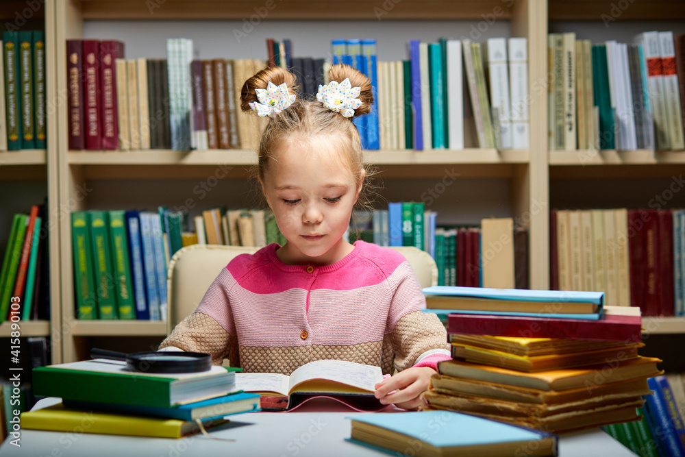 little girl sits with books at table in library,child in bookstore, surrounded by colorful books for school little girl sits with books at table in library,child in bookstore, surrounded by colorful books for school
