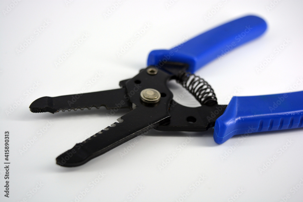 Metal plassentes with blue plastics handles for trimming wires of different diameter located on a white plastic background. Metal plassentes with blue plastics handles for trimming wires of different diameter located on a white plastic background.