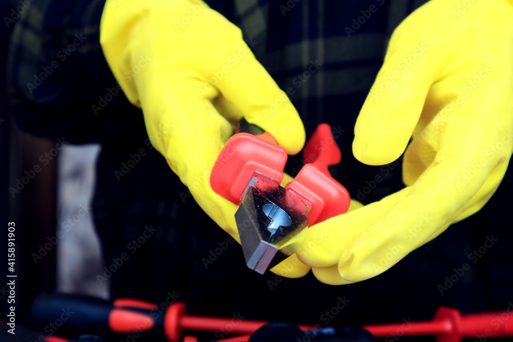 Pliers in the hands of yellow gloves, side view, close-up
