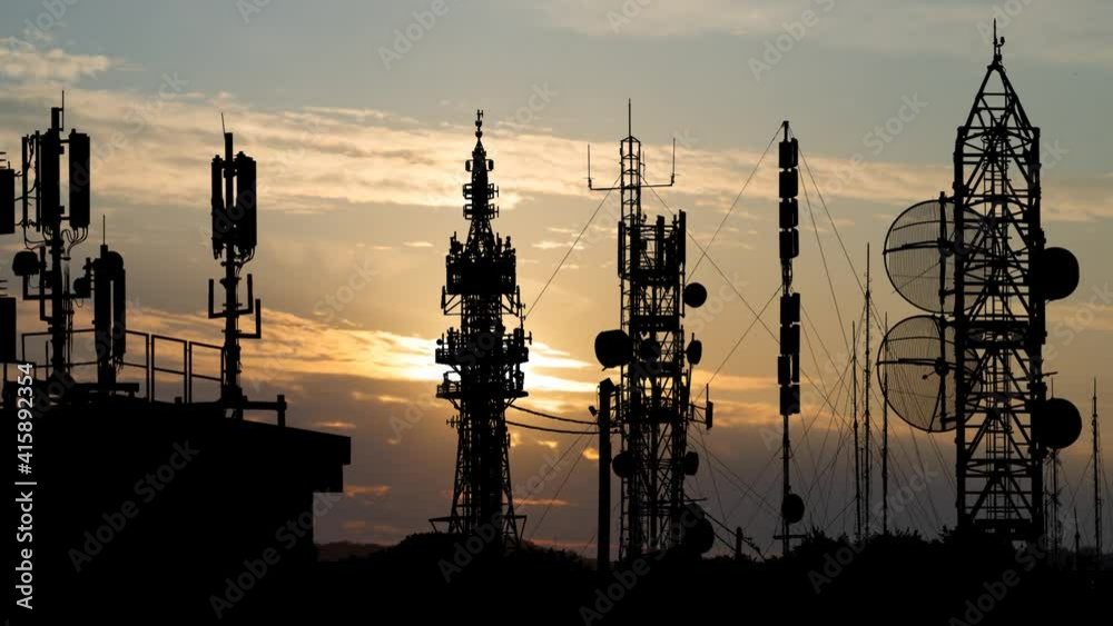Communication Antennas: Time Lapse at Sunrise with Colorful Sky and Silhouette of Modern Towers