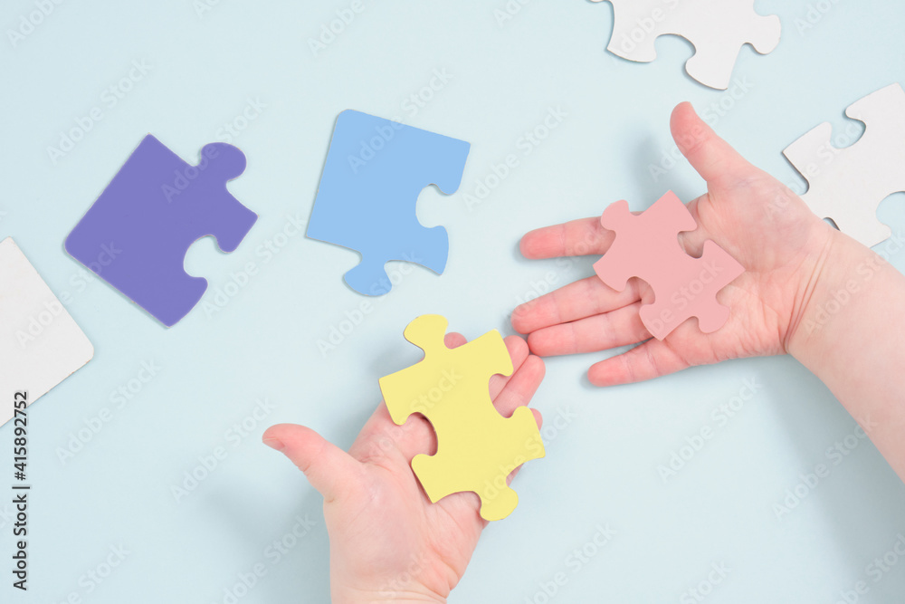 childrens hands holding puzzles on a blue background childrens hands holding puzzles on a blue background