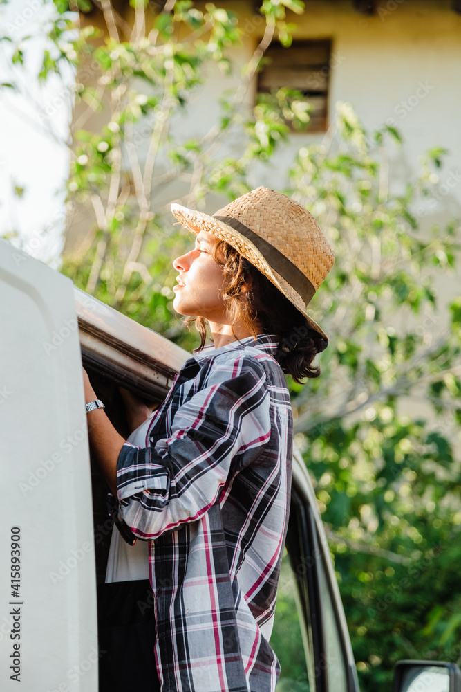 Young farmer woman in a van looking out at crop field