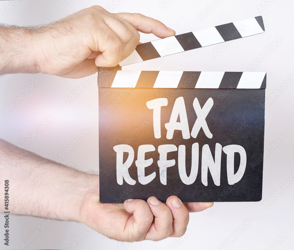 Obraz premium On a white background, a man holds a clapperboard in his hands on which it is written - TAX REFUND