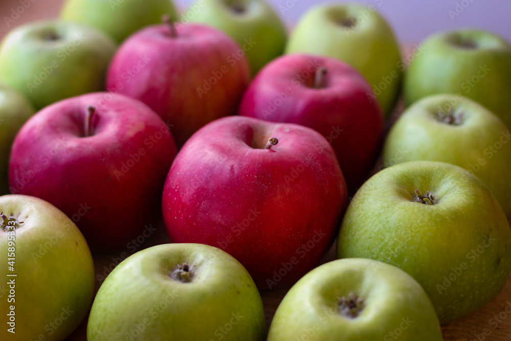 Green and red apples stand on a wooden surface Green and red apples stand on a wooden surface