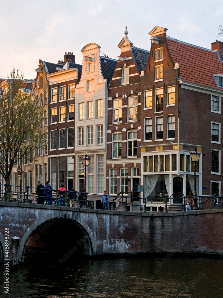 Netherlands, Amsterdam. Traditional houses along the canals and bridge crossing.