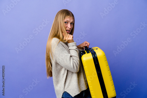 Young russian woman holding suitcase to travel scared and afraid.