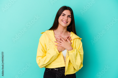 Young caucasian woman isolated on blue background laughing keeping hands on heart, concept of happiness.