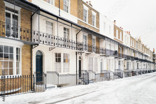 Georgian or Victorian style terrace houses other wise known as row houses in the snow in winter. They have ornate railings and basements