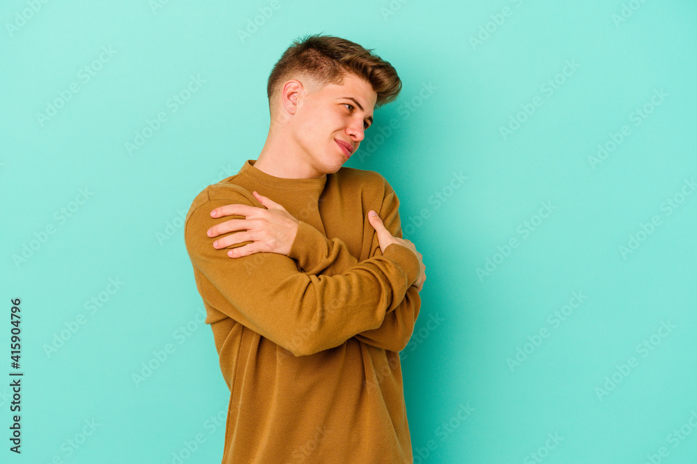 Young caucasian man isolated on blue background hugs, smiling carefree and happy. Young caucasian man isolated on blue background hugs, smiling carefree and happy.