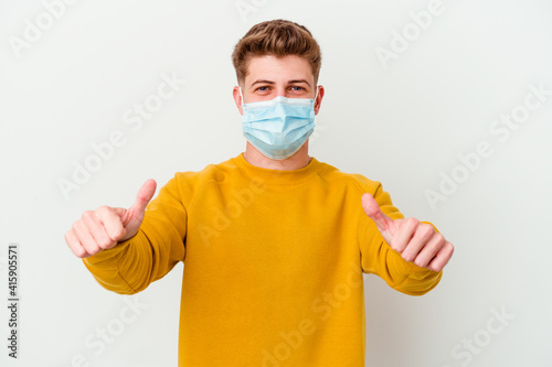 Young man wearing a mask for coronavirus isolated on white background with thumbs ups, cheers about something, support and respect concept.