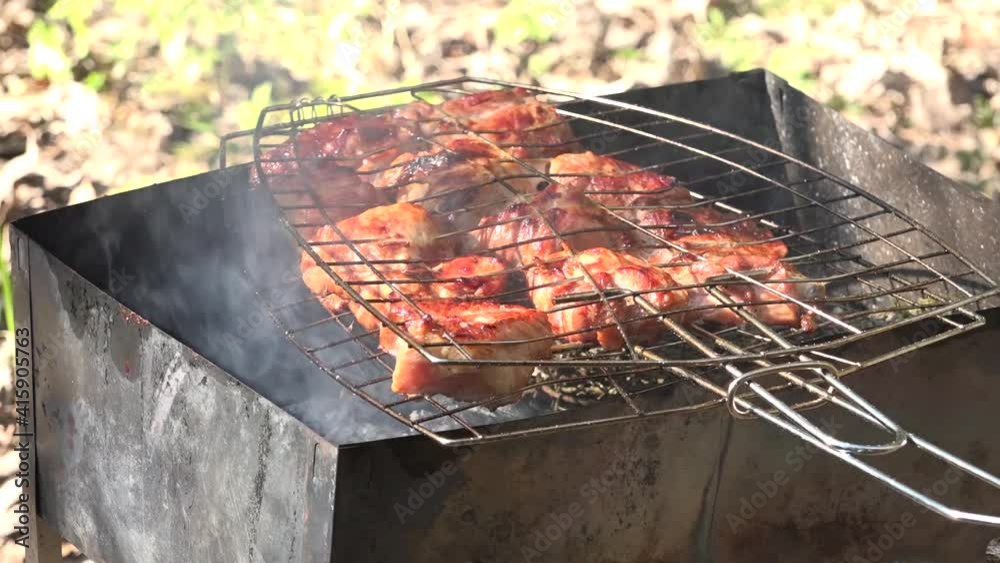 Roasting juicy meat steak with spices and herbs in burning charcoals fire on bbq grid, flames and smoke. Juicy steak with grilling stripes ready for picnic celebration. Barbecue grill Roasting juicy meat steak with spices and herbs in burning charcoals fire on bbq grid, flames and smoke. Juicy steak with grilling stripes ready for picnic celebration. Barbecue grill