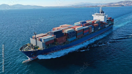 Aerial drone photo of colourful truck size container tanker ship cruising deep blue sea near commercial port of Piraeus, Attica, Greece © aerial-drone