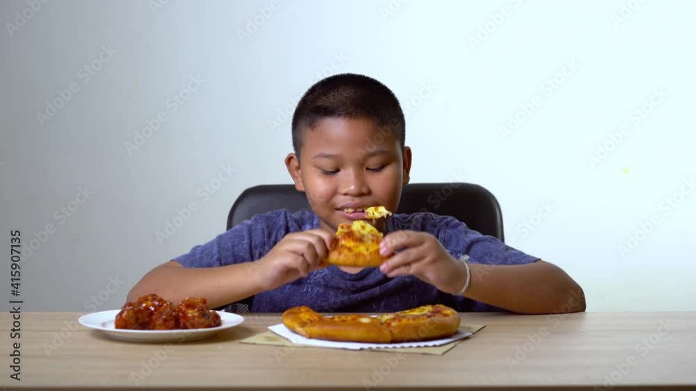 Asian fat boy chose pizza and fried chicken. Concept of child health problems pathogenic food.
Asian fat boy chose pizza and fried chicken. Concept of child health problems pathogenic food.