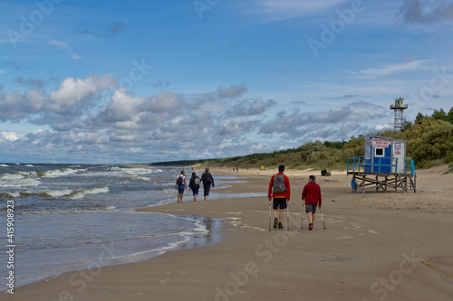 People walk along the beach by the sea