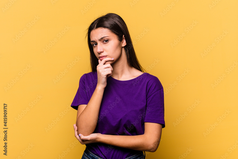 Young Indian woman isolated on yellow background suspicious, uncertain, examining you. Young Indian woman isolated on yellow background suspicious, uncertain, examining you.