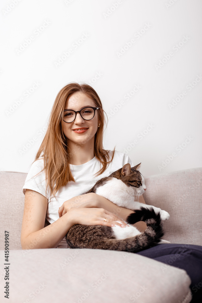 Beautiful woman with cute cat at home. Beautiful middle-aged woman at home on the couch in the interior. Playing with cat at home. Playing with pet. Young woman sitting on couch and hugging pet. Beautiful woman with cute cat at home. Beautiful middle-aged woman at home on the couch in the interior. Playing with cat at home. Playing with pet. Young woman sitting on couch and hugging pet.