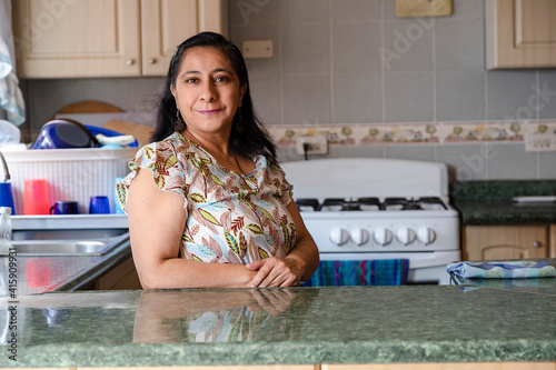 Proud Hispanic woman posing in her kitchen clean-smiling mom standing in the kitchen-woman in the kitchen not cooking photo