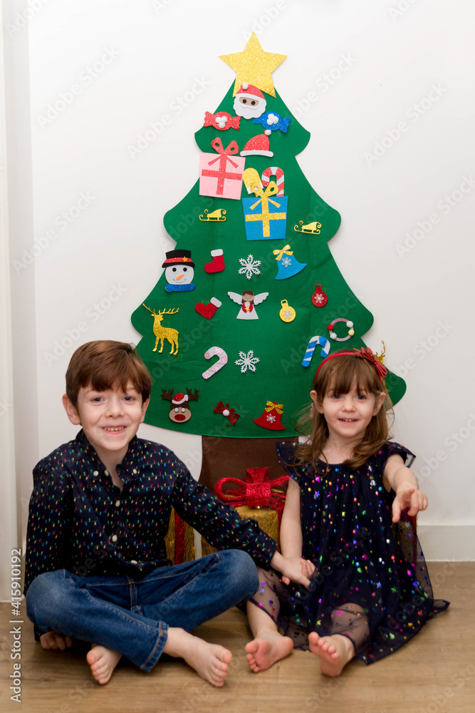 Two children sitting in the floor in front of a Christmas tree