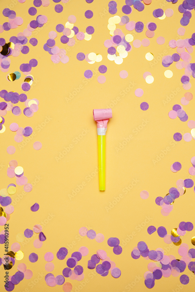 Party horn and scattered shiny confetti on orange background Party horn and scattered shiny confetti on orange background
