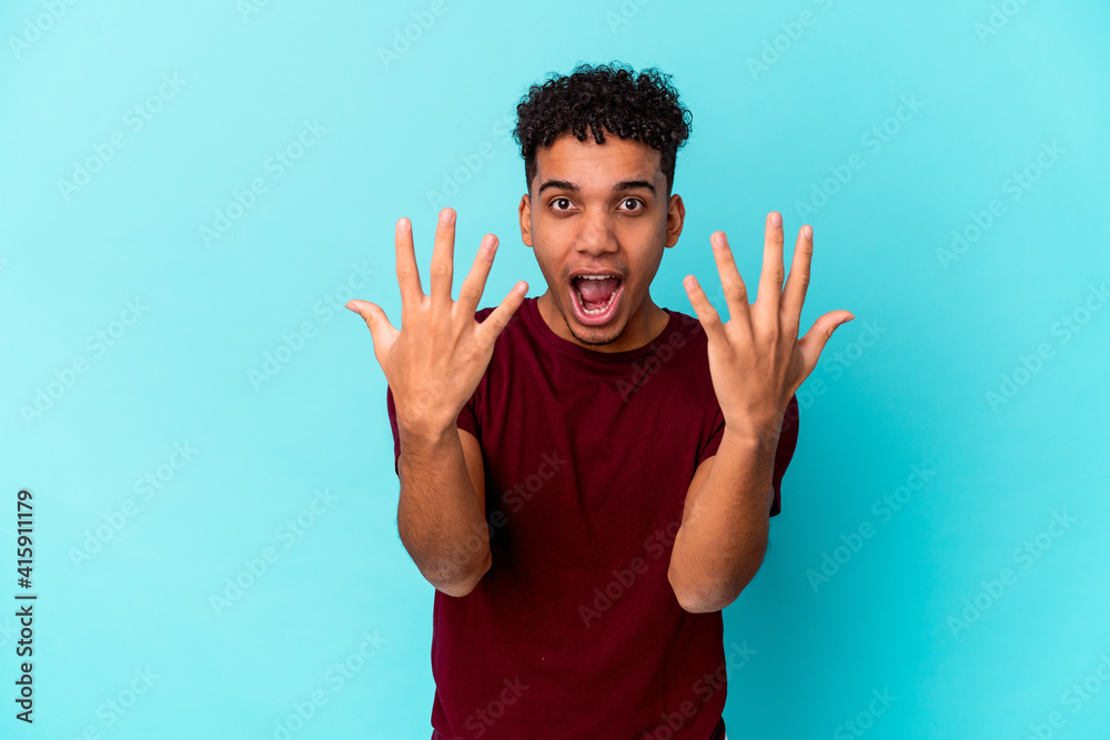 Young african american curly man isolated on blue showing number ten with hands. Young african american curly man isolated on blue showing number ten with hands.