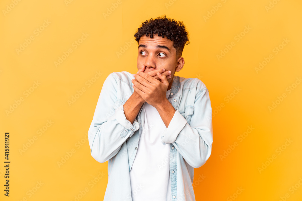 Young african american curly man isolated on purple thoughtful looking to a copy space covering mouth with hand. Young african american curly man isolated on purple thoughtful looking to a copy space covering mouth with hand.