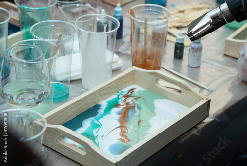 workshop on painting wooden pallets with epoxy resin. Plastic cups with colored resin, on the table, close-up. Painstaking work with gloves. Hobbies, entertainment