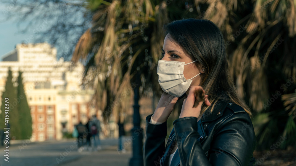 Fototapeta premium Chica joven con mascarilla de protección en el parque