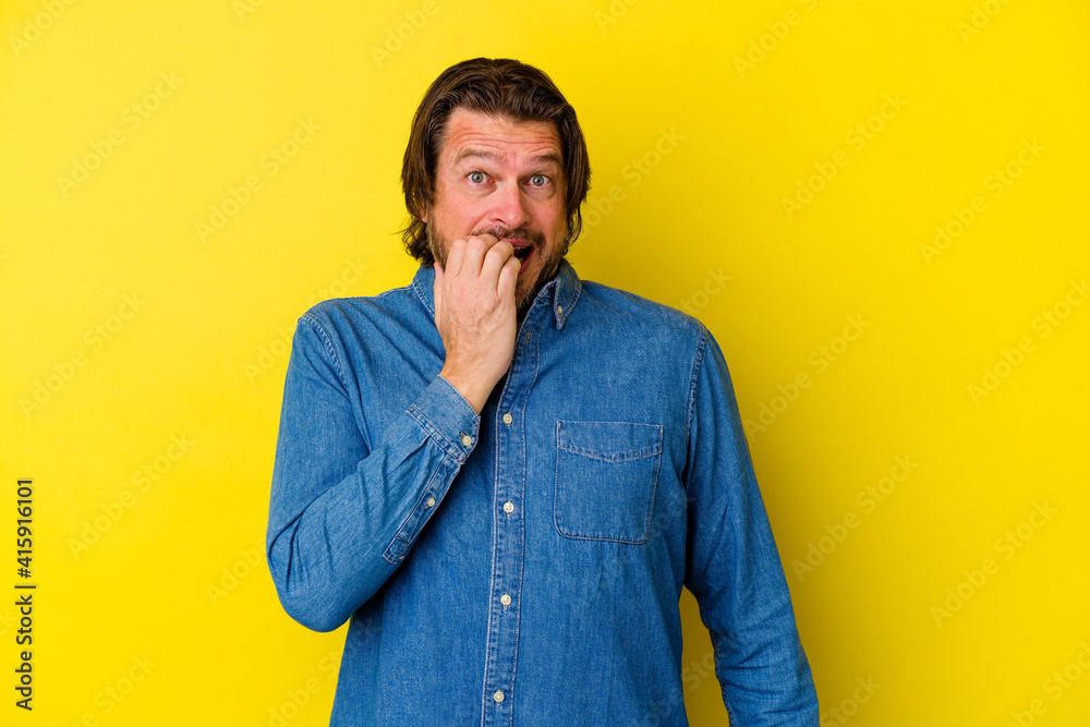 Middle age caucasian man isolated on yellow background biting fingernails, nervous and very anxious.