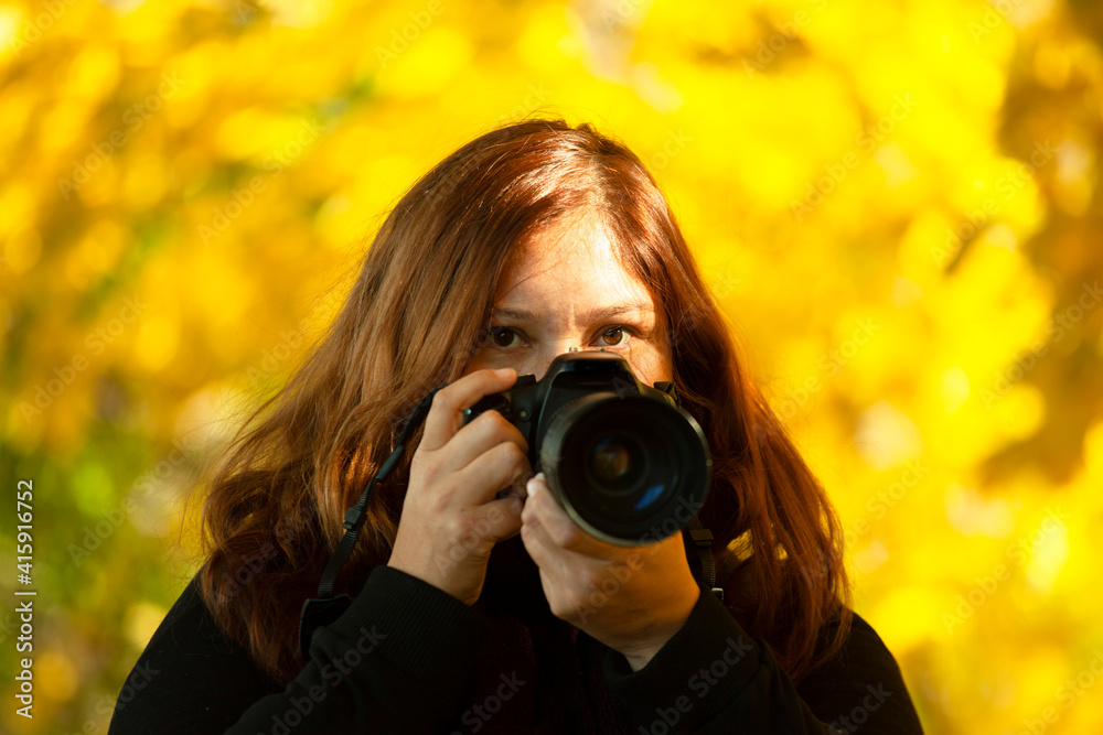 Pretty Female Photographer looks into Camera and holds a professional DSLR
