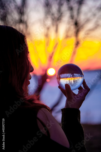 Native Girl looking into Crystal Ball on the Shore of a frozen Lake with a Magical Sunset