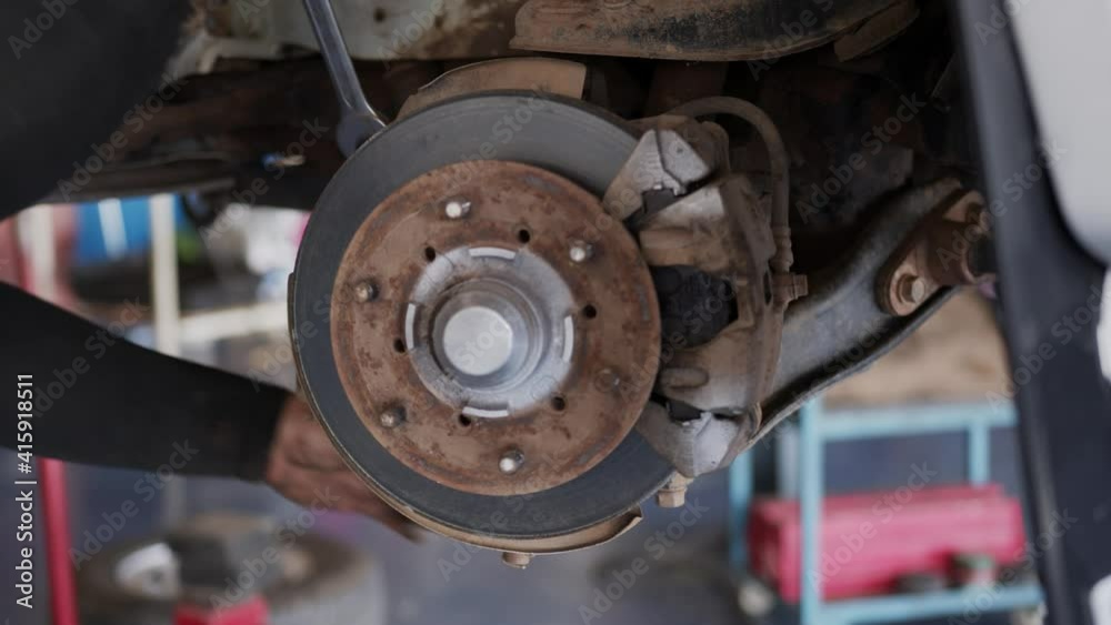Motor vehicle mechanic is removing wheels in a car workshop. Motor vehicle mechanic is removing wheels in a car workshop.