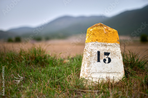 milestone or milepost sign on a rural road with hills in the bac photo