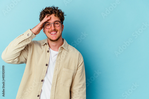 Young caucasian man wearing eyeglasses isolated on blue background shouts loud, keeps eyes opened and hands tense.