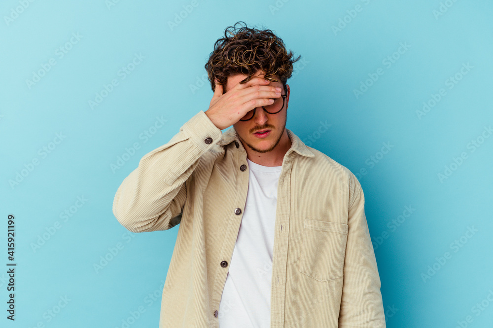Young caucasian man wearing eyeglasses isolated on blue background touching temples and having headache. Young caucasian man wearing eyeglasses isolated on blue background touching temples and having headache.