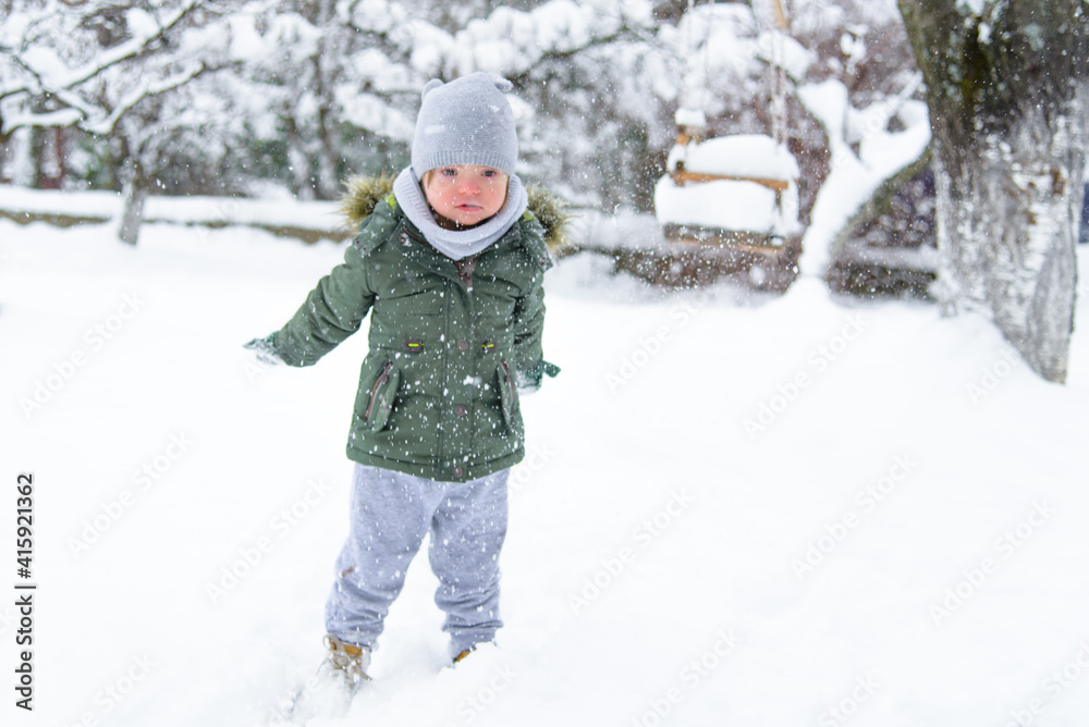 Down syndrome toddler boy throws snowflakes from his hands. Blurred. Disabled boy enjoys the frosty winter weather and snow. Winter fun in the yard. Frosty weather. Winter breath. Snow explosion