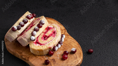 Homemade biscuit sweet roll with cranberries and cream on a black table, copy space