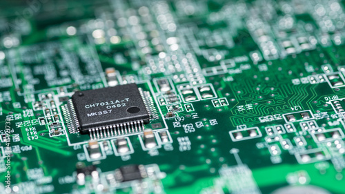 Fragment of a green computer printed circuit board with selective focus on an abstract microchip, horizontal panoramic