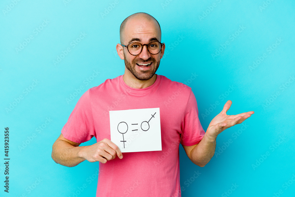 Young caucasian bald man holding a equality gender placard isolated on yellow background receiving a pleasant surprise, excited and raising hands. Young caucasian bald man holding a equality gender placard isolated on yellow background receiving a pleasant surprise, excited and raising hands.