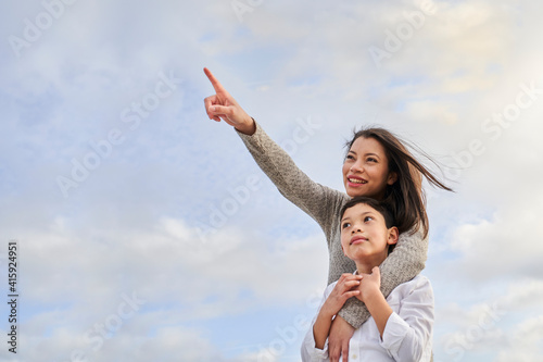 Young Latina mother with child pointing to some point. Family concept.