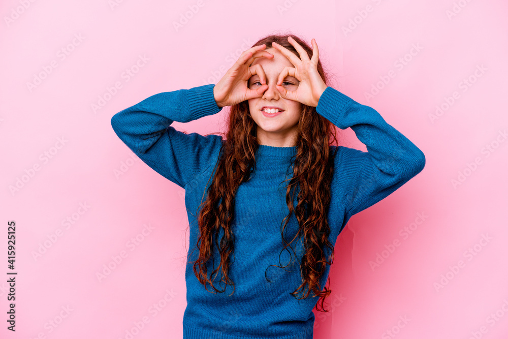 Little caucasian girl isolated on pink background excited keeping ok gesture on eye.