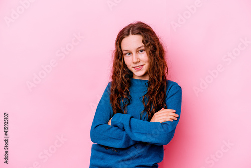 Little caucasian girl isolated on pink background who feels confident, crossing arms with determination.