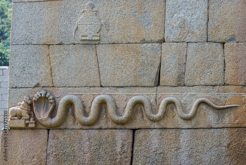 Chitradurga, Karnataka, India - November 10, 2013: Fort or Elusuttina Kote. Closeup of snake sculpture on main entrance gate wall in brown-gray stone. photo