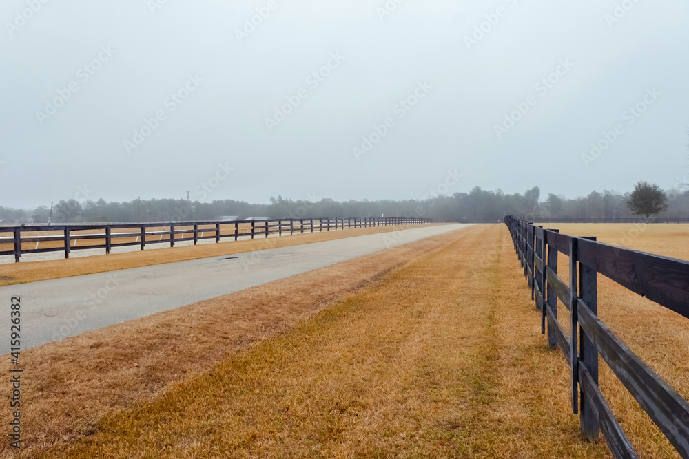 Rural road. Strong fog and country farm in the morning. Wooden fence.
