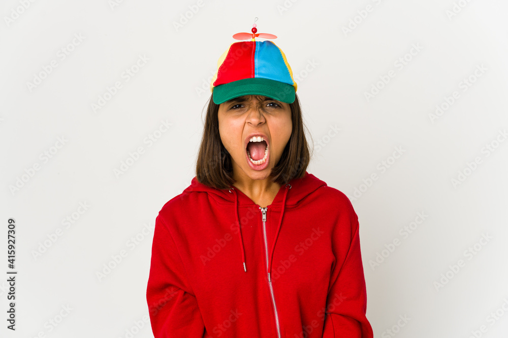 Young hispanic woman wearing a cap with propeller isolated screaming very angry and aggressive. Young hispanic woman wearing a cap with propeller isolated screaming very angry and aggressive.