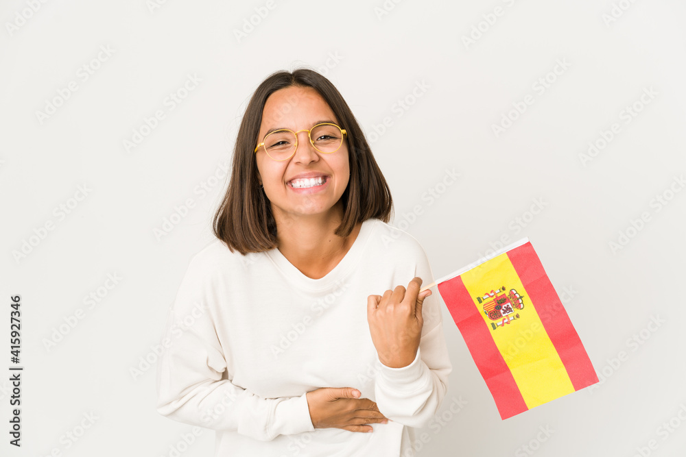 Young hispanic mixed race woman holding a spanish flag laughing and having fun. Young hispanic mixed race woman holding a spanish flag laughing and having fun.